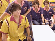 a group of people are sitting around a table in a bowling alley and one of them is wearing a yellow shirt