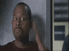 a man in a red shirt is making a surprised face .