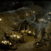 a group of people sitting around tables in front of a tent at night