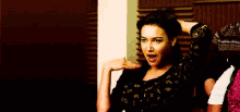 a woman is standing in a room with her hand on her head and making a funny face .