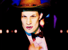 a man wearing a cowboy hat holds his finger to his lips