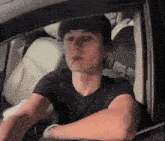 a man in a black shirt is smoking a cigarette while driving a car .