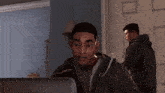 a man in a hoodie is looking at a computer screen in a room .
