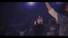 a woman sings into a microphone in front of a crowd of people