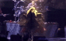a woman is dancing on a stage in front of a drummer