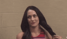 a woman in a red and black striped top is holding her hair .