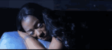a woman is sleeping on a blue pillow in a dark room .
