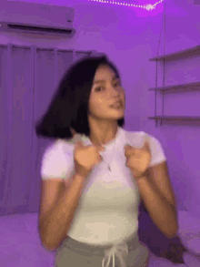 a woman is standing in a room with purple lights on the wall .