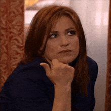 a woman with her hand on her chin looks to her left