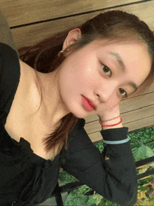 a woman wearing a black top has her hand on her chin