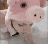 a woman wearing a pink pig hat and a bow tie is laying in a bathtub .