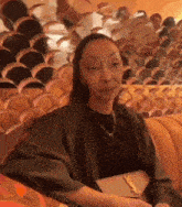 a woman is sitting on a couch holding a purse and looking at the camera .