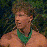 a shirtless man with curly hair is wearing a green bandana around his neck and a hat .