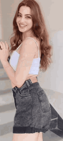 a woman in a white tank top and black shorts is smiling .