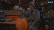 a man in a ghostbuster costume is carving a pumpkin on a bench .