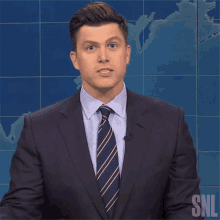 a man in a suit and tie stands in front of a snl map