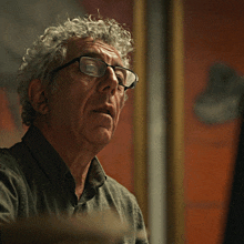 a close up of a man wearing glasses and a green shirt