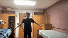 a man in a black shirt is standing in a room with a mattress