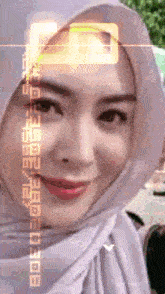 a woman wearing a white hijab is smiling and looking at the camera with a glowing square on her forehead