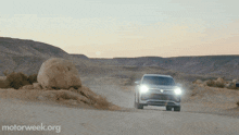 a car is driving down a dirt road in the desert