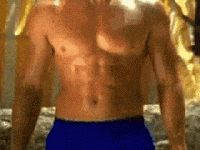 a shirtless man wearing blue shorts is standing in front of a wall .