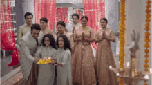 a group of people are standing next to each other in a room holding a plate of food .