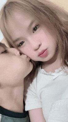 a little girl is being kissed on the cheek by her father