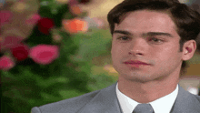 a man in a suit and tie is crying in front of some flowers