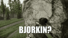 a person holding a sniper rifle in front of a rock with the words bjorkin written on it