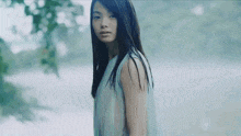 a woman with long hair is standing in front of a body of water .