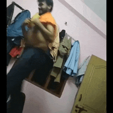 a shirtless man is standing in a room with clothes hanging on the wall ..