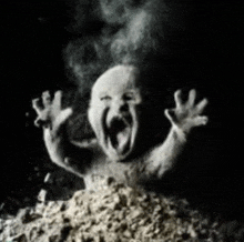 a black and white photo of a baby screaming in a pile of sand .