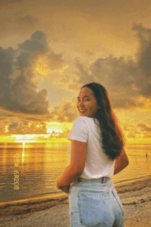 a woman stands on a beach with a sunset in the background and a date stamp of 8/29/2020