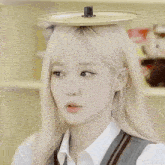 a girl with blonde hair is wearing a hat with a lid on her head .