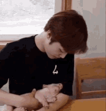 a man is sitting at a table holding a small pig .