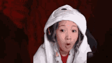 a woman wearing a hoodie and headphones is sitting in front of a microphone .