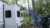 a man is using a tractor to lift a trailer in the woods