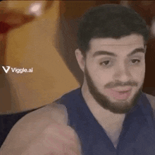 a man with a beard and a blue tank top is smiling and making a funny face .