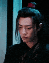 a man with long hair is wearing a black jacket and a red headband