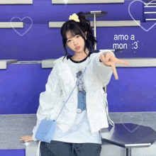 a girl in a white jacket is pointing at the camera with the words amo a mon written below her