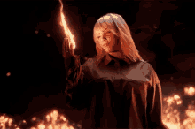 billie eilish is holding a torch in her hand in a dark room .