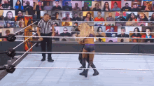two women are wrestling in a ring with a referee and a crowd watching