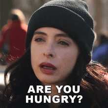 a woman wearing a black beanie is asking if she is hungry