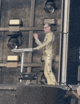 a man in a gold suit is standing on a stage playing a keyboard