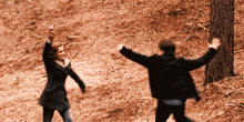 a man and a woman are dancing in a field with their arms outstretched
