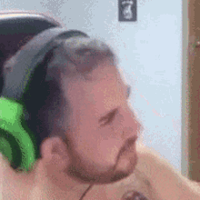 a man with a beard is wearing green headphones and a tattoo on his arm .