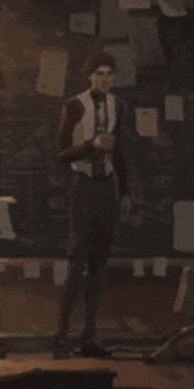 a man in a suit is standing in front of a blackboard holding a glass of wine .