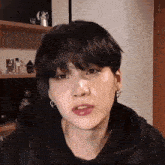 a close up of a person 's face with a black hoodie and earrings .