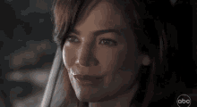 a close up of a woman 's face smiling while sitting in a car .