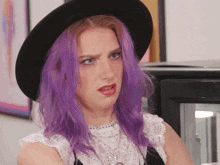 a woman with purple hair is wearing a black hat and a white top